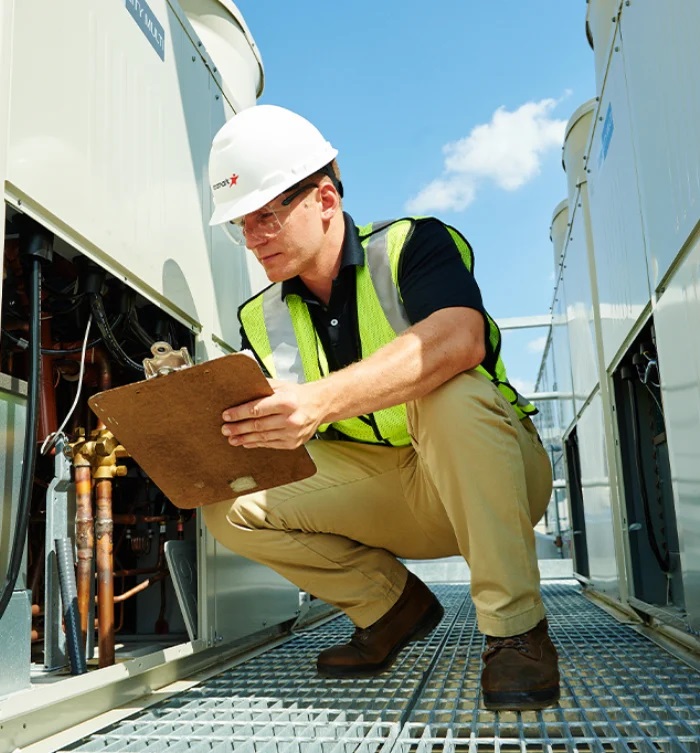 Aramark employee holding a clipboard examining equipment on a rooftop.